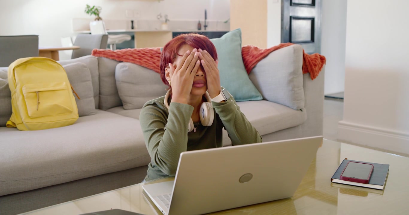 African American woman staring at silver laptop after long study session, rubbing eyes and typing