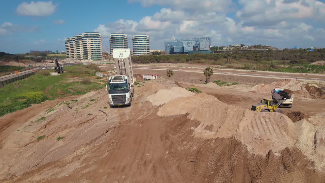 camión volquete descargando arena en la construcción situada para construir un nuevo barrio junto al mar en un día nublado