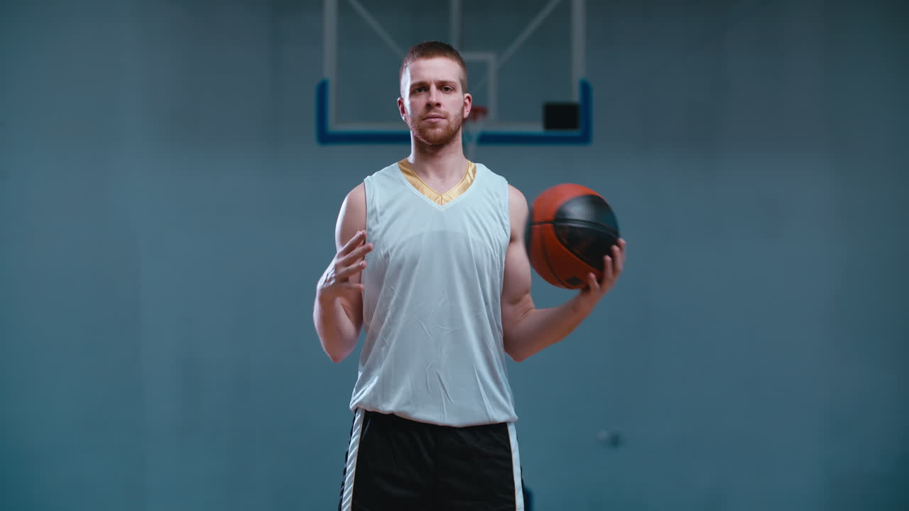 retrato de media longitud de un jugador de baloncesto caucásico posando con una pelota en el interior. 4k uhd