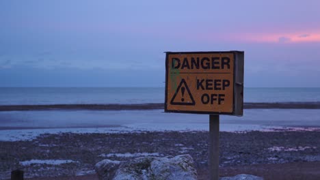 Gefahr---Gelbes-Schild-Am-Strand-Bei-Sonnenaufgang-Fernhalten