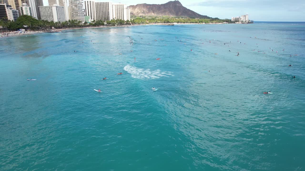 Surfisti che cavalcano le onde in una località tropicale per il surf mentre un drone sorvola acque cristalline e blu e cieli soleggiati