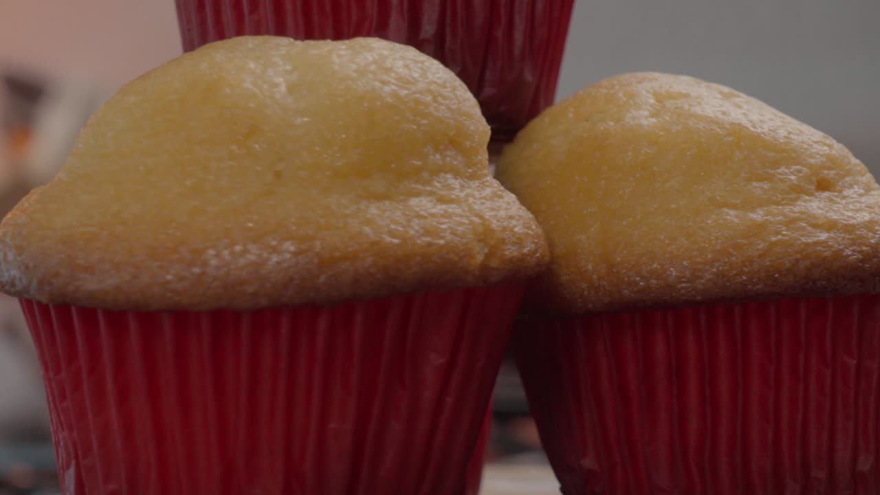 A detailed close-up of freshly made tamales and beautifully decorated cupcakes on display at a local market, showcasing a mix of traditional and sweet treats perfect for any occasion.
