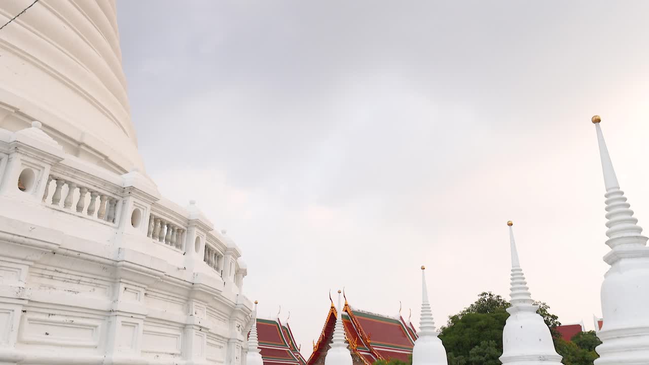 A tranquil video capturing the architectural beauty of Wat Prayurawongsawat in Bangkok, showcasing its white stupas and ornate details