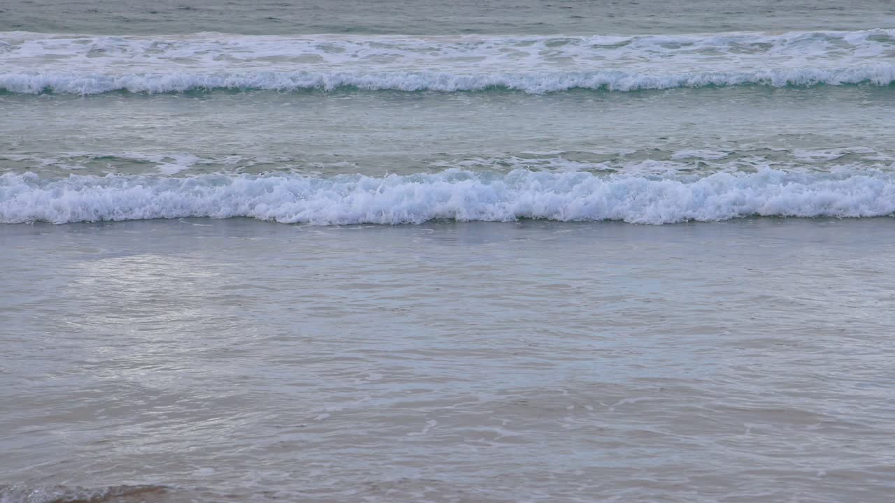 Gentle waves roll onto the shore at Great Ocean Road, captured in soft, natural lighting with a serene atmosphere