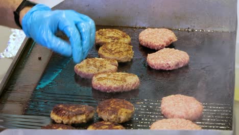 rindfleisch wird in einer heißen bratpfanne gekocht. straßenessen, der koch dreht burger mit einem spatel.