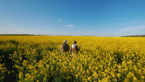 people walking through a yellow rapeseed field