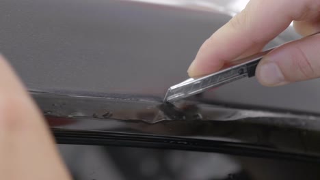 cutting excess car wrapping foil at vehicle door with utility knife