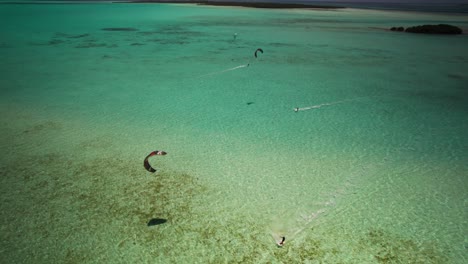 los kiteboarders se deslizan sobre las aguas cristalinas en los rocas, vista aérea