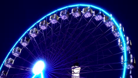 4k view of illuminated ferris wheel rotates against a dark sky.