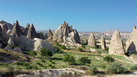 Epic-cinematic-aerial-drone-shot-of-a-man-standing-on-a-hill-top-looking-at-the-fairy-chimneys-in-Cappadocia,-Turkey