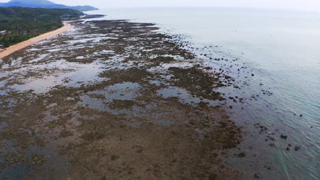 Shallow-seabed-uncovered-by-low-tide-on-tropical-ocean-coast,-Thailand