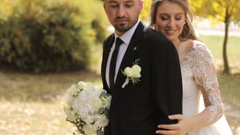 a happy bride and groom embrace in an autumn park