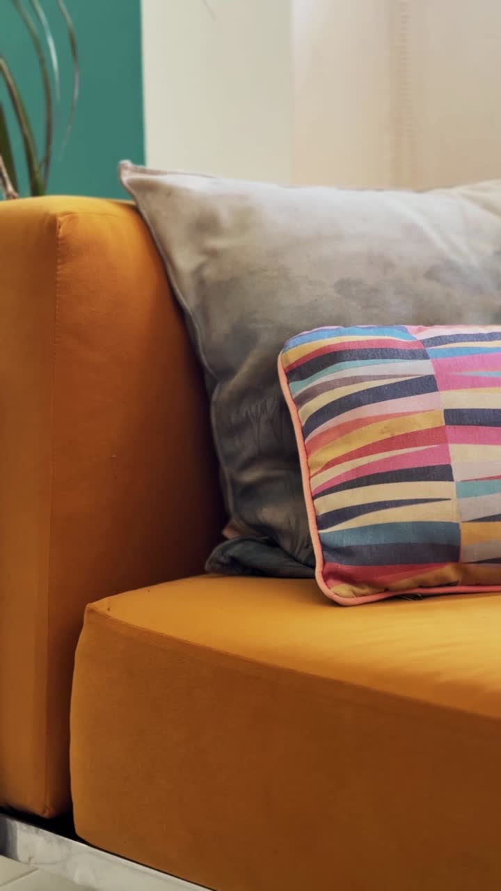Moderne sennepsgul sofa med farverige puder i et hyggeligt rum