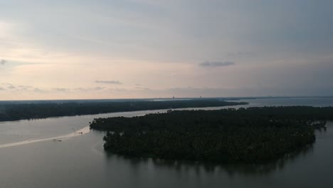 Hermosa-Toma-Aérea-De-Una-Isla-De-Aguas-Estancadas,-Lago-Vembanad-Asia,-Transporte-De-Agua-Al-Atardecer