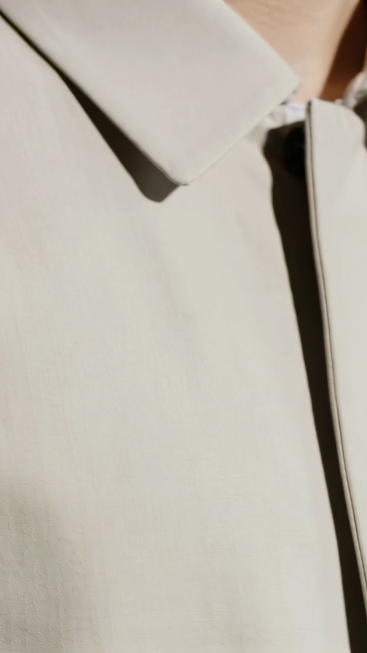 Vertical video: Panning camera revealing beige coat in studio showing concealed placket for detail