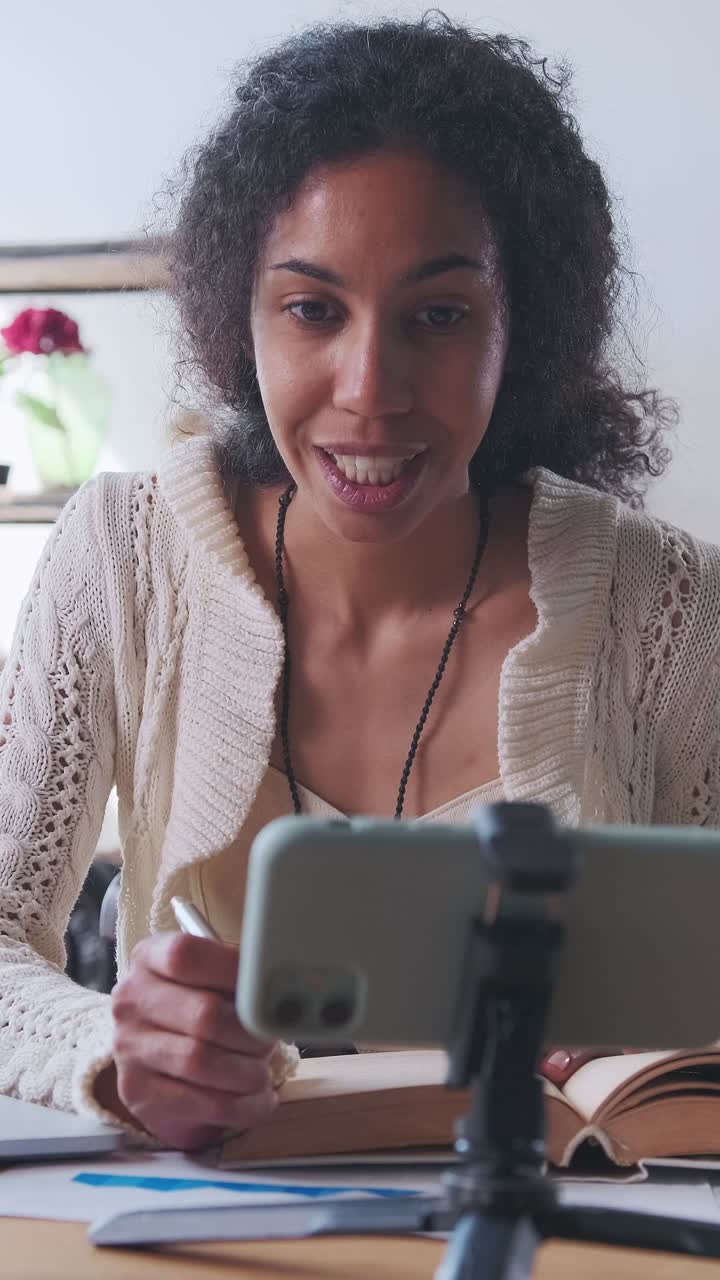 Young african american woman recording online webinar on mobile phone camera