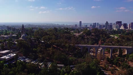 Luftpanoramablick-über-Den-Balboa-Park-Area-Bezirk-Von-San-Diego-Kalifornien,-Städtische-Brückenstraßen-Straßen-Und-Gebäude-Auf-Dem-Grünen-Hügelpark,-Stadtbild-Der-Innenstadt-Mit-Coronado-brücke-Im-Horizont