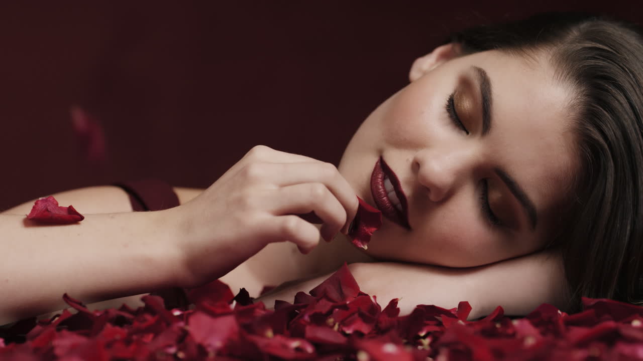 ritratto bella donna caucasica che gioca con petali di rosa toccando pelle morbida donna sensuale che sogna fantasia intima romanzo indulgente desiderio in rosso concetto di giorno di san valentino