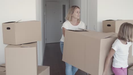 positive mom and daughter carrying cartoon box