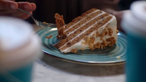 cerca de una persona comiendo una rebanada de pastel de zanahoria con un tenedor