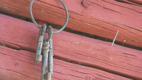 Old-fashion-vintage-keys-hanging-on-rustic-textured-red-wall,-tilt-down