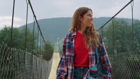 happy girl traveling mountains at summer holiday. woman hiking on river bridge.