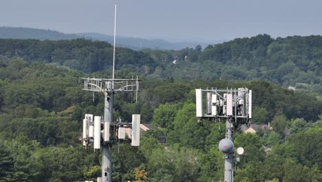 two telecommunication transmission tower in rural suburb area of american town. housing area between green trees background. aerial view