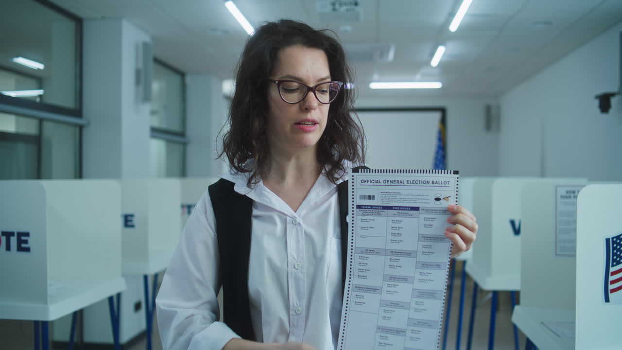 American Female Voter Looks and Speaks on Camera Shows Paper Ballot American Female Voter Looks and Speaks on Camera Shows Paper Ballot Calls for Voting National Election Day in the United States Voting Booths at Polling Station Civic Duty and Patriotism Concept