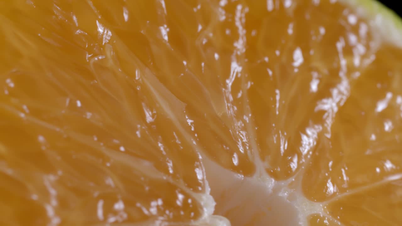Video ravvicinato di un mandarino affettato che ruota su sfondo nero.