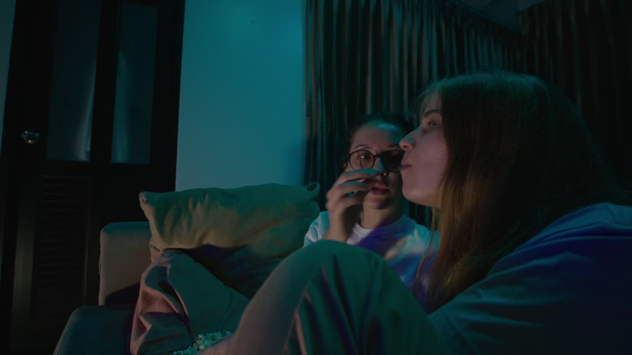 Two friends watching a movie at home at night