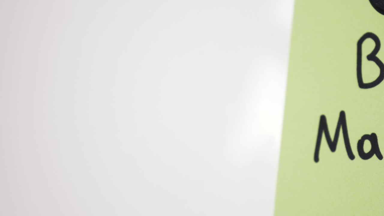 Pan reveal of Bull Market text on green note held by magnet on whiteboard with selective focus