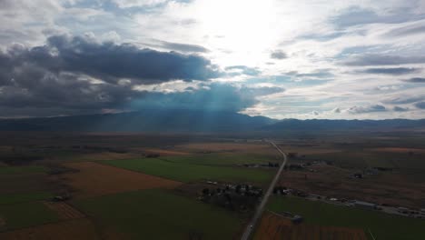 drone shot of sunlight coming through clouds with mountains in the distance