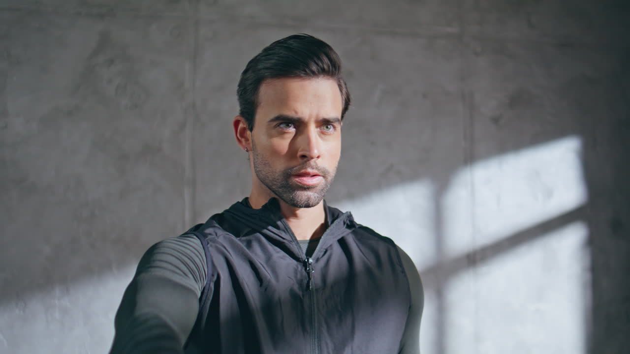 Focused athlete exercising dumbbells in loft studio closeup. Strong man lifting