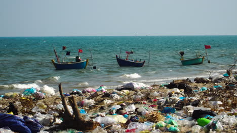 traditional boats with flag floating in the sea with garbage on the beach