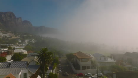 Vuele-Sobre-El-Barrio-Residencial-En-Un-Día-Brumoso.-Cresta-De-La-Montaña-Rocosa-En-El-Fondo.-Ciudad-Del-Cabo,-Sudáfrica