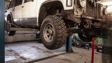 auto repair shop, professional mechanic working on off road vehicle in lifting machine at the garage, time lapse