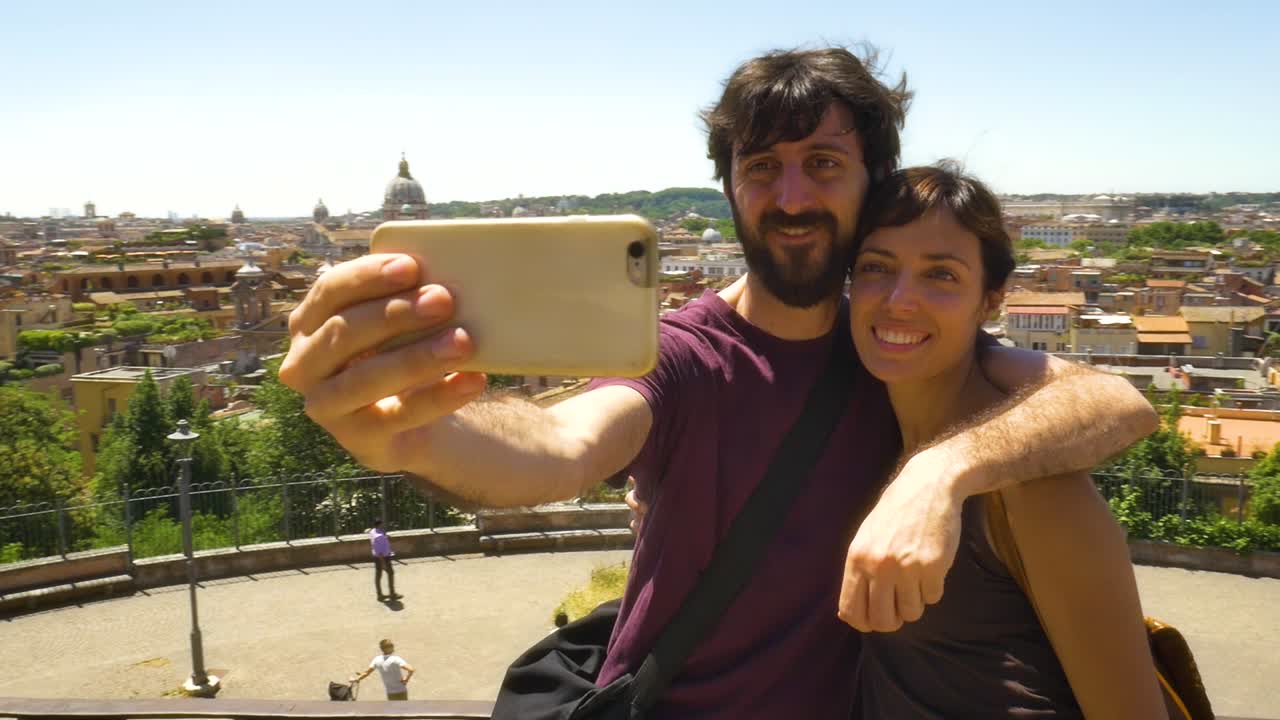 una pareja joven tomando una selfie con el paisaje urbano de roma.