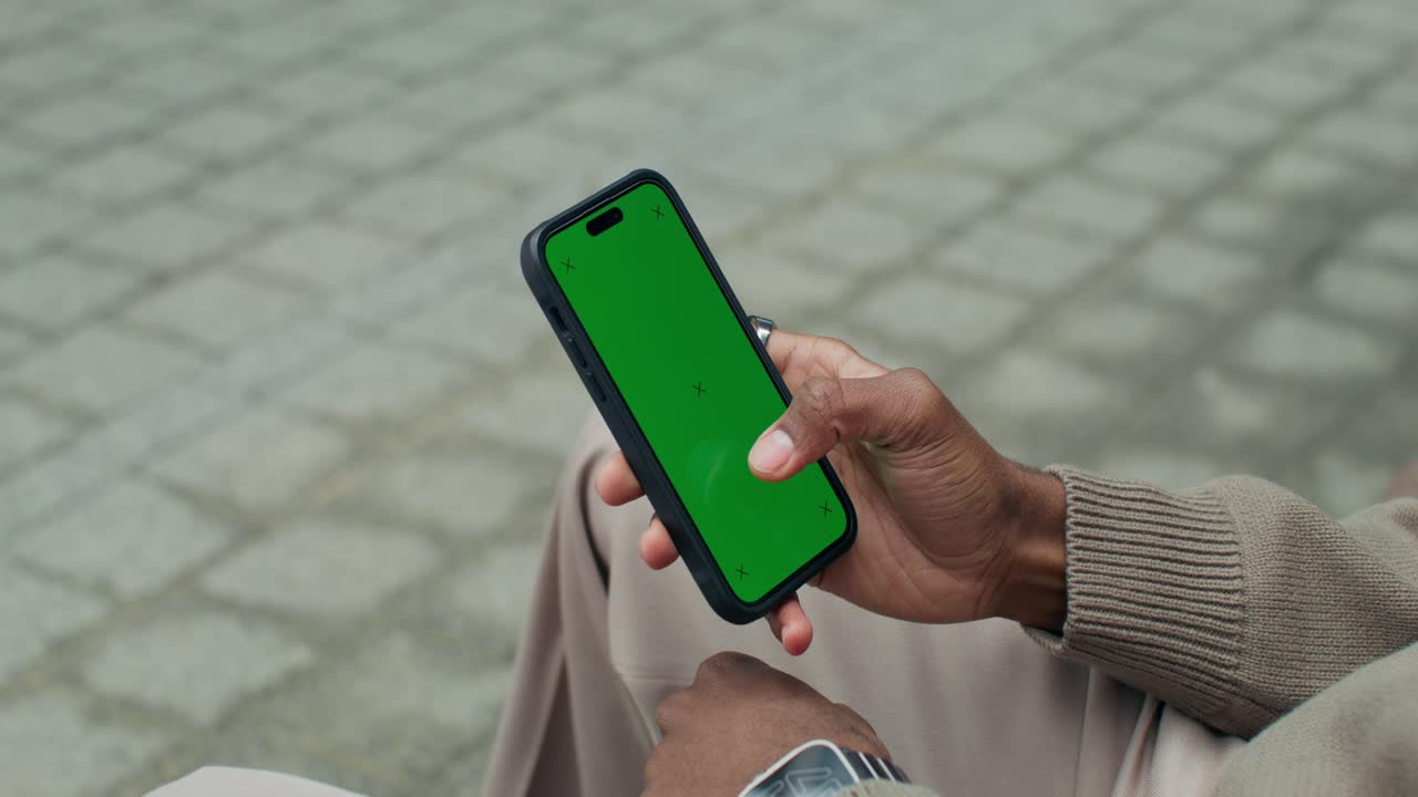 Person, der holder en smartphone med en grøn skærm