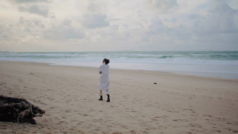 Thoughtful-woman-walking-shore-on-winter-day.-Peaceful-tourist-watching-ocean