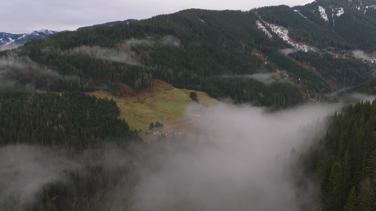 montañas nebulosas con laderas verdes en saalbach-hinterglemm, austria, vista aérea