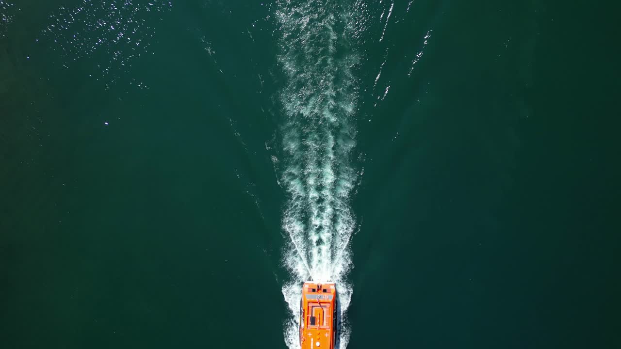 Aerial tilt down view of zodiac boat on sail, wake pattern on greenish water - 4k