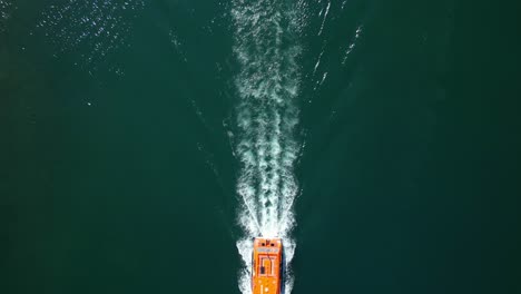 aerial tilt down view of zodiac boat on sail, wake pattern on greenish water - 4k