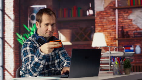 happy man excited to do online shopping, typing debit card information on laptop