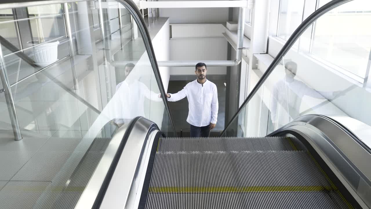 Man Standing on Escalator in Modern Office Building