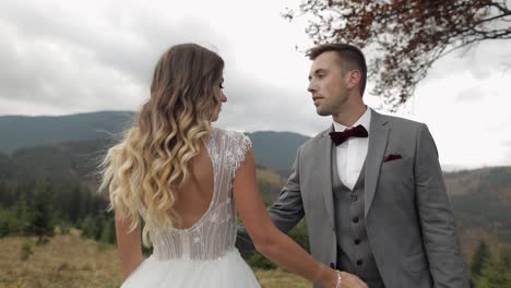 Lovely-young-newlyweds-bride-groom-embracing-on-mountain-slope,-happy-wedding-couple-family-in-love