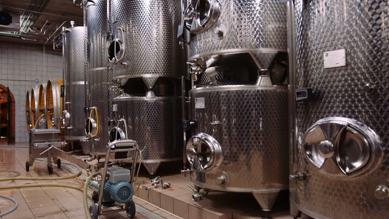 Tilt-up shot reveals big stainless steel vessels used for fermentation of wine