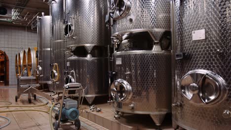 tilt-up shot reveals big stainless steel vessels used for fermentation of wine