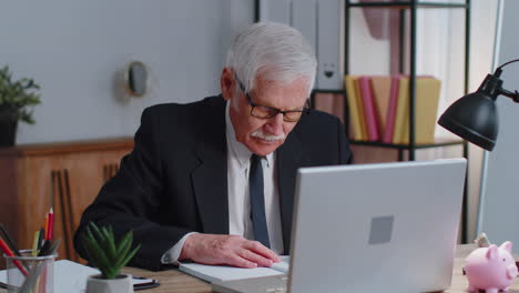 senior business office man analyzes financial charts celebrate success win at home workplace desk