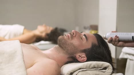beautician gently spraying soothing mist on a man's face during relaxing treatment