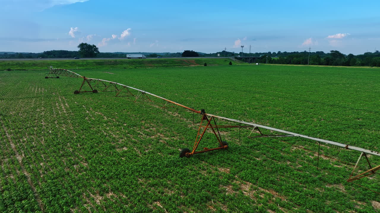 Footage along the system of irrigation in the farm. Flying over the green agricultural filed in summer.